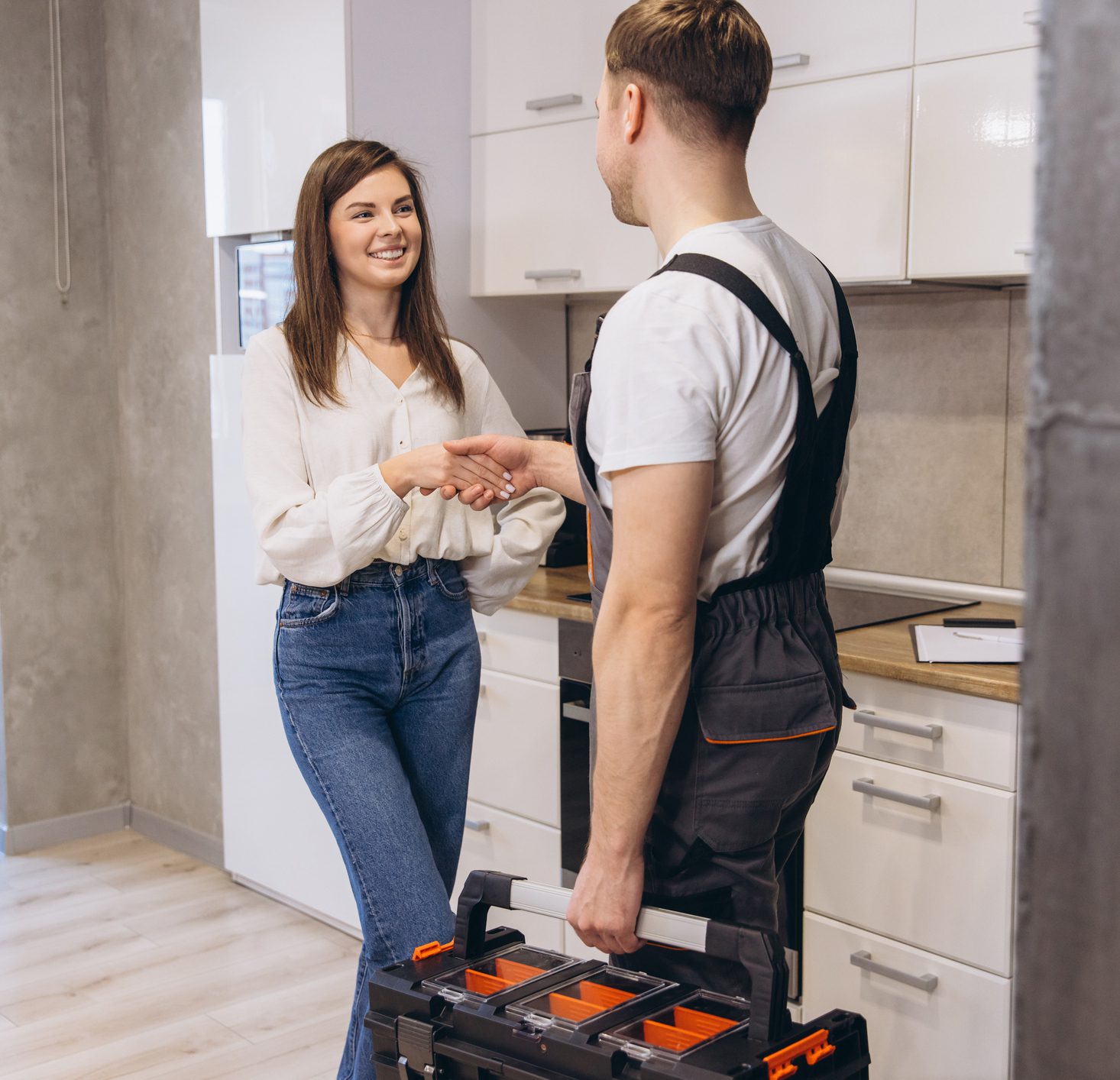Plumber shaking hands with woman after finishing work in kitchen Home