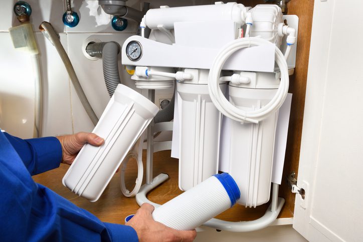Technician installing reverse osmosis equipment under the sink detail water filtration